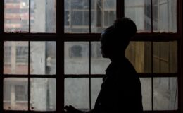 Silhouette of a woman looking out a large window.