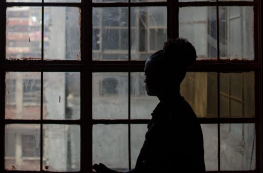 Silhouette of a woman looking out a large window.