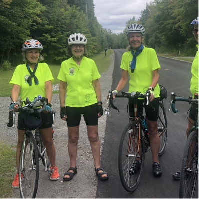 three woman posing at the sid of the road with their bikes