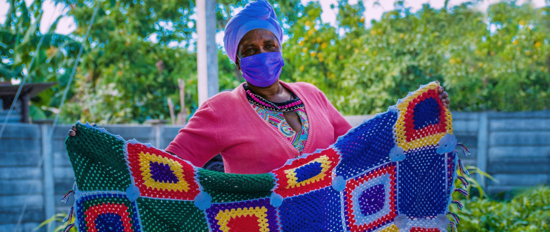 woman holding a colourful crochet blanket