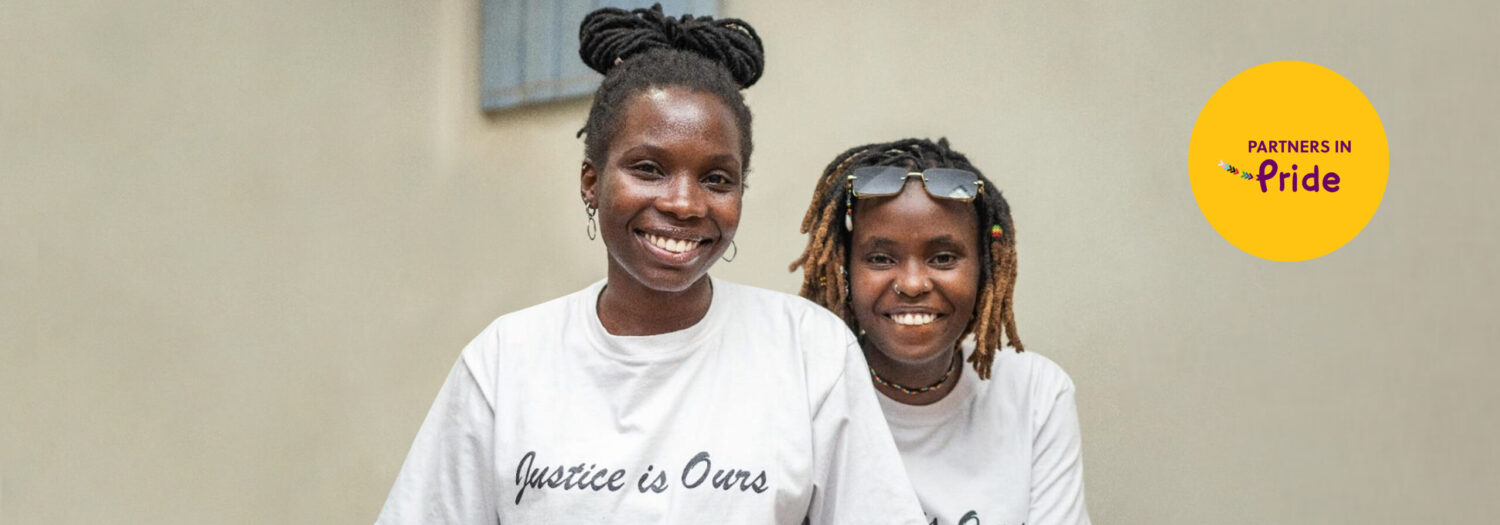 Two young women looking at the camera, smiling. They are wearing a t-shirt with a slogan 