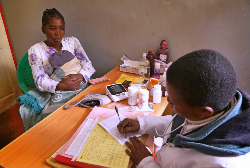 woman holding her baby sitting at a desk and consulting with a health professional